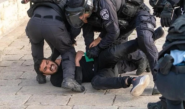 Israeli forces brutally assaulting a Palestinian man in the courtyard of al-Aqsa Mosque on 17 April 2022 (Mahmoud Moutan)