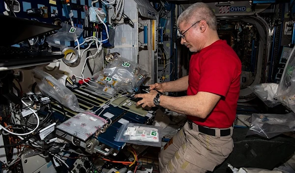 NASA astronaut Mark Vande Hei sets up components for a space botany study