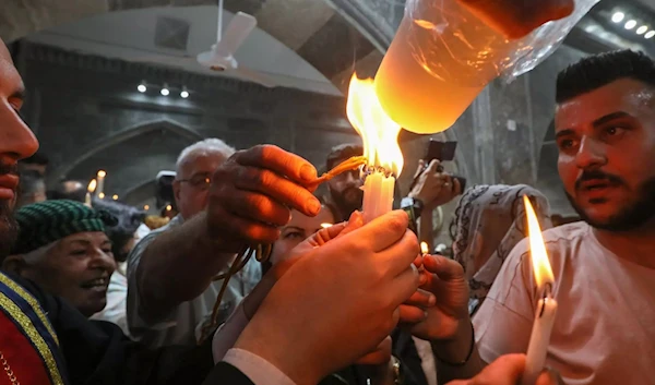 Iraqi Orthodox Christians share the flame of the "Holy Fire" brought from Al-Quds (AFP)