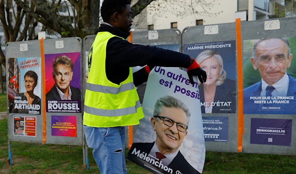 France Affichage Plus workers paste official campaign posters of French Presidential election candidates on electoral panels in Saint-Herblain near Nantes, France, March 28, 2022 (Reuters)