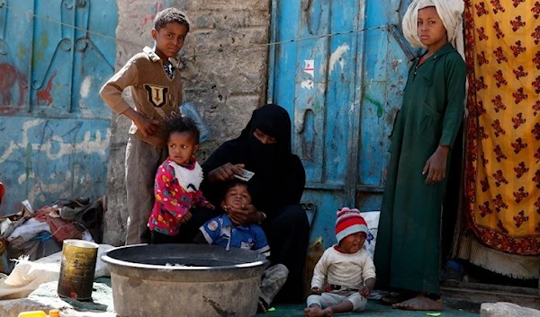 A displaced woman sits among her children outside a temporary shelter in Sanaa, Yemen, 7 February 2020 (Yahiya Arhab/EPA/EFE)