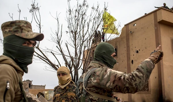 YPG terrorists standing in front of a building, northeastern Syria, March 24, 2019. (Getty Images)