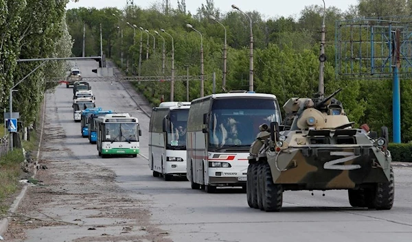 Buses carrying Azov fighters who have surrendered after weeks holed up at Azovstal steelworks drive away under the escort of the Russian forces, May 17, 2022 (REUTERS)