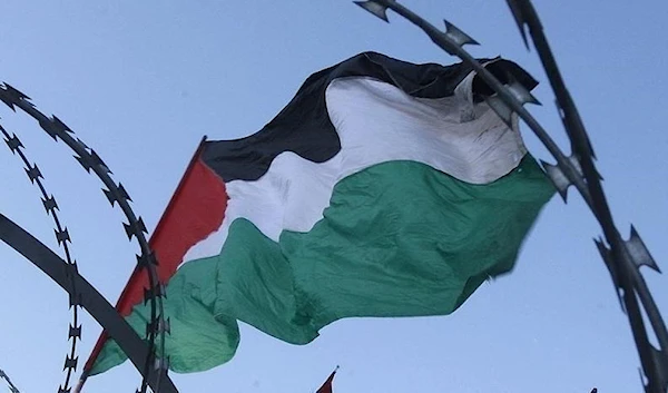 Palestinian flag waves freely above barbed wire