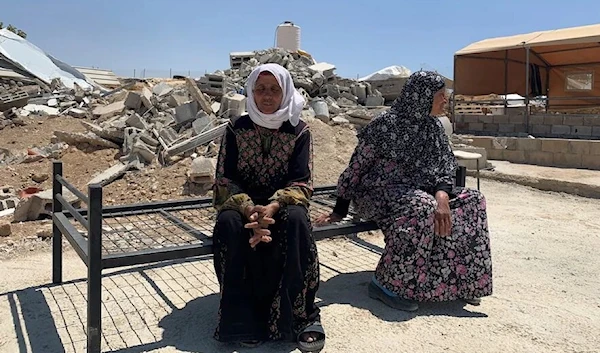 Safa Muhammed Aba al-Najjar, left, and Yusara al-Najjar sit on a bed frame in front of what used to be their house in the West Bank, before it was demolished by the Israeli army on May 11. (The Washington Post)