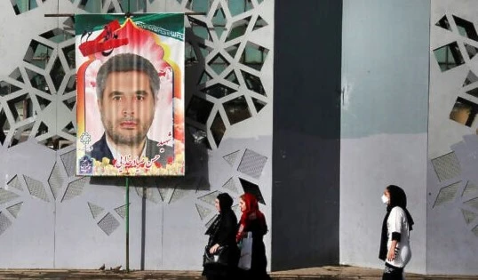 Iranians walk past a banner showing Col. Hassan Sayyad Khodaei who was assassinated on Sunday. (AP)