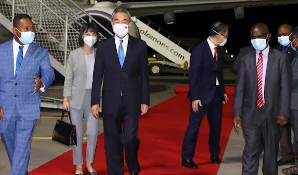 China's Foreign Minister Wang Yi, center, is escorted from his plane on his arrival in Honiara, Solomon Islands, May 26, 2022. (AP)