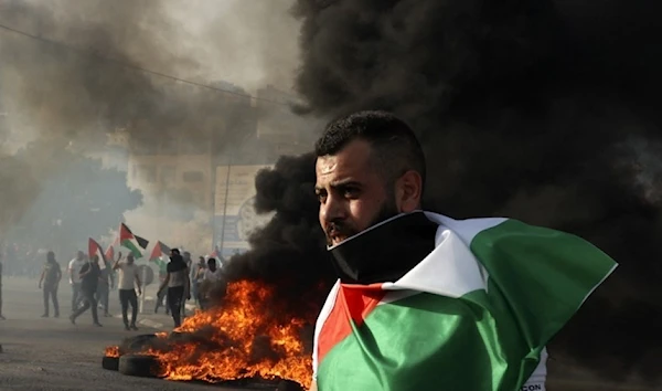 A protester drapes the Palestinian flag around his shoulder at the Hawara Checkpoint near Nablus in the occupied West Bank.