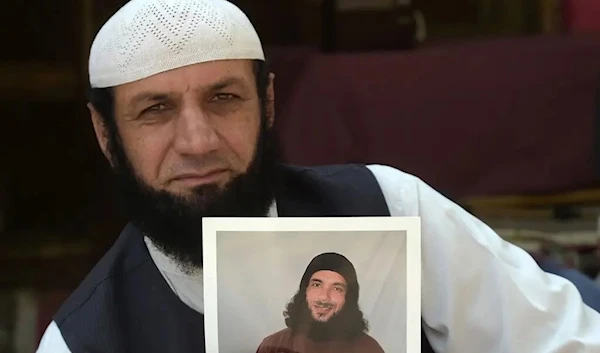 Roman Khan holds a photo of his brother, Assadullah Haroon Gul, who was unjustly and illegally held in Guantanamo Bay for 15 years (AFP)