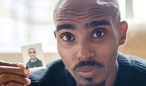 Sir Mo Farah holds up a picture of himself as a child during the filming of the BBC documentary. (BBC)