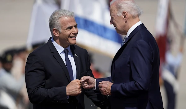 US President Joe Biden is greeted by Israeli occupation Prime Minister Yair Lapid at Ben Gurion Airport, Al-Lydd, occupied Palestine, July 13, 2022 (AP)