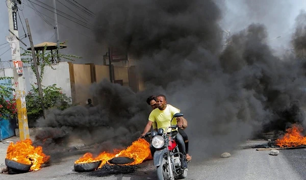 A motorcycle driver passes through a burning roadblock amid gang violence, in Port-au-Prince, Haiti, July 13, 2022 (Reuters)