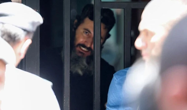 A man who security sources said was armed and holding hostages while demanding the return of his bank deposits, is seen through the door of the Federal Bank of Lebanon in Hamra, Lebanon, August 11, 2022 (Reuters)