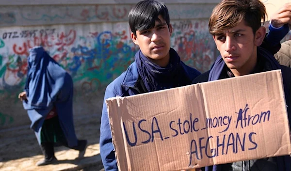 Afghan protesters hold placards and shout slogans against US during a protest condemning President Joe Biden's decision, in Kabul, Afghanistan, Feb. 12, 2022.