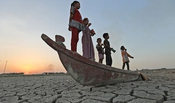 Children stand on a boat lying on the dried-up bed of southern Iraq's receding Chibayish Marshes - Asaad NIAZI  Read more: https://www.al-monitor.com/originals/2022/08/iraqs-garden-eden-now-desert#ixzz7bulmYzwn