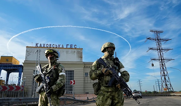 Russian troops guard an entrance of the Kakhovka Hydroelectric Station, a run-of-the-river power plant on the Dnieper River in Kherson region, southern Ukraine, Friday, May 20, 2022, during a trip organized by the Russian MoD