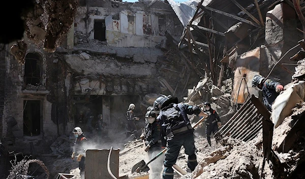 Donetsk People's Republic Emergency Situations Ministry employees clear rubble at the side of the damaged Mariupol theater building on May 12, 2022