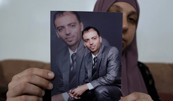 Dalal, the wife of Khalil Awawdeh, a Palestinian prisoner in Israeli occupation prisons, displays his picture at the family house, in the West Bank town of Idna, west of al-Khalil, Wednesday, Aug. 17, 2022 (AP Photo/Nasser Nasser)