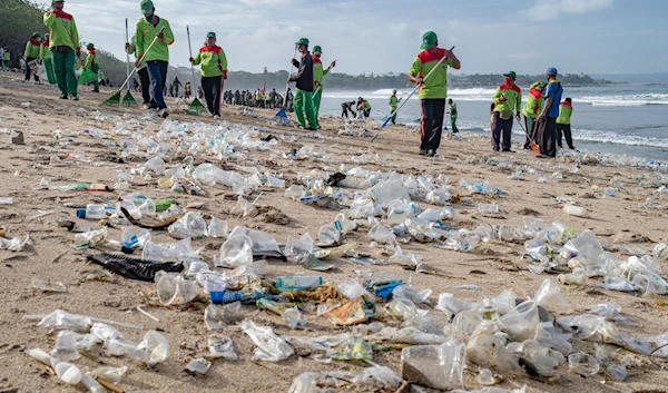 Workers clean up piles of debris and plastic waste brought in by strong waves at Kuta Beach in Bali, Indonesia, on January 1, 2021