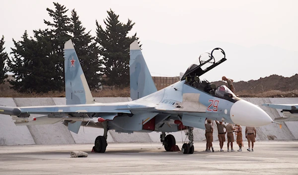 In this photo taken on Thursday, Oct. 22, 2015, Russian air force personnel stand near a Russian war plane at Hemeimeem airbase, Syria (AP Photo/Vladimir Isachenkov)