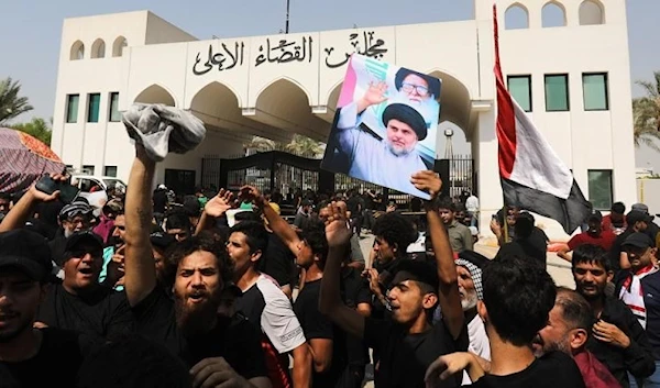 Supporters of Muqtada Al-Sadr, head of the Sadrist movement, carry his picture in front of the Supreme Judicial Council, Baghdad, Iraq, 23 August 2022 (EPA)