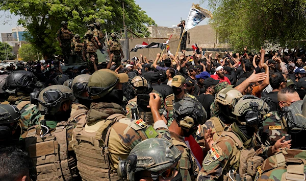 Soldiers standby as supporters of Muqtada al-Sadr protest in front the Supreme Judicial Council, in Baghdad, Iraq, Tuesday, Aug. 23, 2022 (AP Photo/Hadi Mizban)