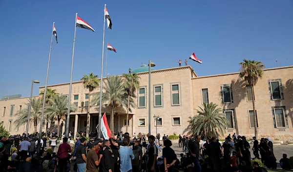 A supporter of Muqtada al-Sadr waves a national flag from the roof of the Government Palace during a demonstration in Baghdad, Iraq, Monday, Aug. 29, 2022