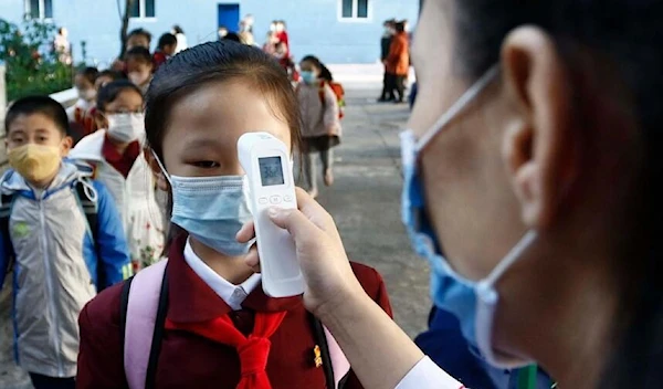 A teacher takes the body temperature of a schoolgirl before entering Primary School in Pyongyang. (AP)