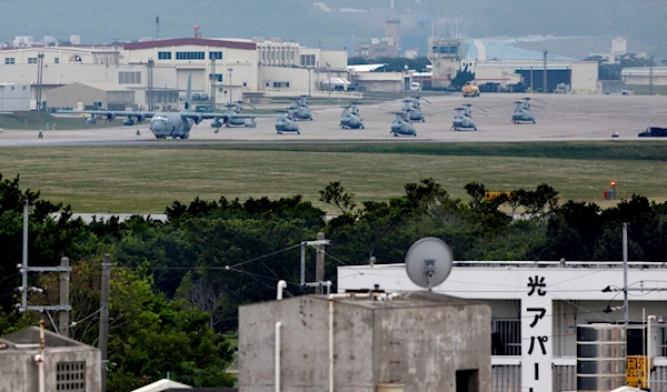 A military plane and helicopters are seen at Marine Corps Air Station Futenma behind a residential area in Ginowan, Okinawa prefecture, Japan, on Dec. 17, 2009 (AP Photo/Shizuo Kambayashi, File)