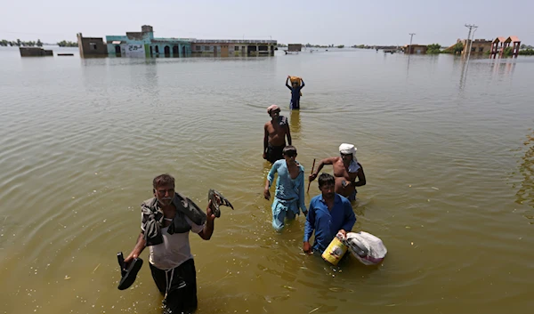 Victims of flooding from monsoon rains carry belongings salvaged from their flooded home in the Dadu district of Sindh Province, of Pakistan, Sept. 9, 2022 (AP Photo/Fareed Khan, File)