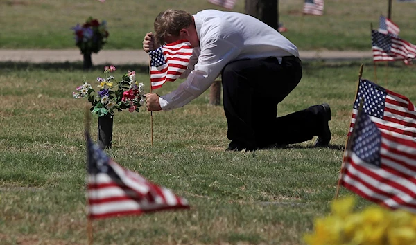 James Kohr places an American flag at a veteran's grave at Sunset Memorial Gardens in Odessa, Texas, on May 28.Jacob Ford / Odessa American via AP file.