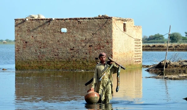 A man carries some belongings as he wades through floodwaters in Jaffarabad. (Archive)