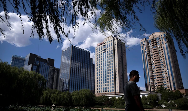 A man walks past a lily pond at a public park on a sunny day in Beijing, Thursday, Sept. 22, 2022 (AP Photo/Mark Schiefelbein)