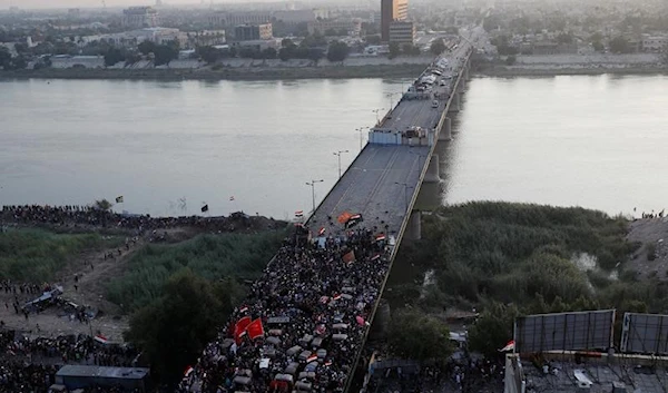 Demonstrators take cover in front of Iraqi security forces at Al Jumhuriya bridge bridge during anti-government protests in Baghdad, Iraq October 30, 2019