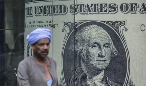 A man walks past a currency exchange shop displaying a giant US dollars banknote in downtown Cairo.( AFP)