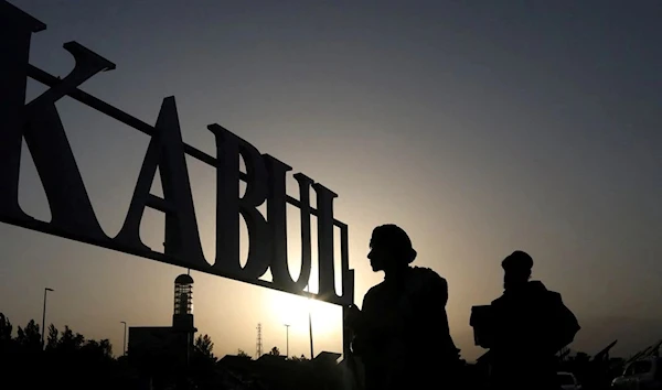 Taliban soldiers stand in front of a sign at the international airport in Kabul, Afghanistan (REUTERS)