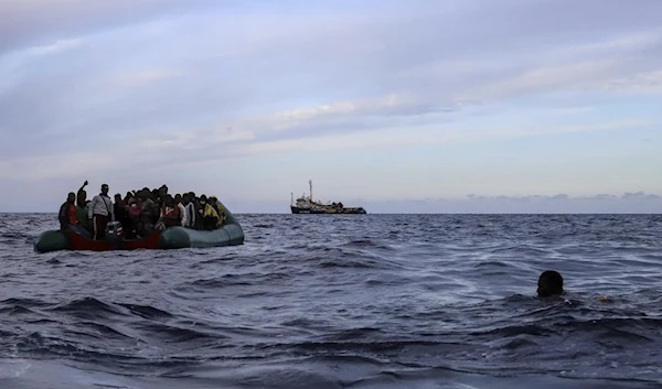 A migrant who was aboard a precarious rubber boat with others jumps to the water as they are rescued by a team of the Sea Watch-3, around 35 miles away from Libya, in Libyan SAR zone, Monday, Oct. 18, 2021 (AP)