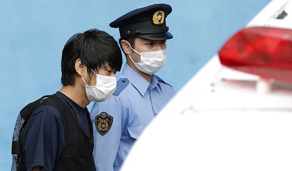 Tetsuya Yamagami is escorted by a police officer as he is taken to prosecutors, at Nara-nishi police station in Nara, western Japan, July 10, 2022 (Kyodo).