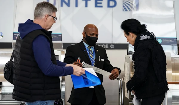 A United Airlines worker assists travelers at Ronald Reagan Washington National Airport in Arlington, Virginia, U.S., April 19, 2022 (Reuters).