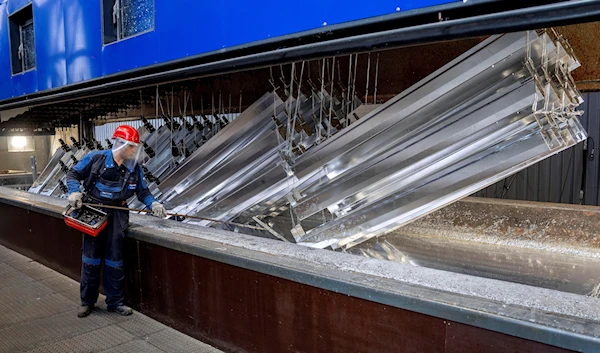 A worker moves metal pieces that are hot-dip galvanized in the Zinkpower galvanizing company in Meckenheim, Germany, Thursday, Aug. 18, 2022 (AP Photo/Michael Probst)