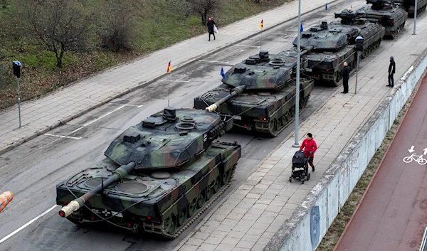 People walk past German Leopard 2 tanks ahead of a rehearsal for the Armed Forces Day military parade marking its 100th anniversary, in Vilnius, Lithuania, Friday, Nov. 23, 2018 (AP Photo/Mindaugas Kulbis)