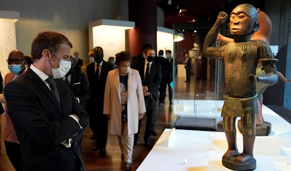 French President Emmanuel Macron looking at a 19th century royal statue representing Benin's King Ghezo (AFP)