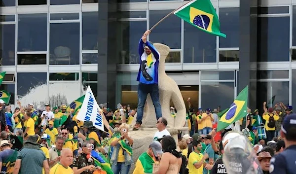 Supporters of Brazilian former President Jair Bolsonaro invade Planalto Presidential Palace while clashing with security forces in Brasilia on January 8, 2023 (AFP)