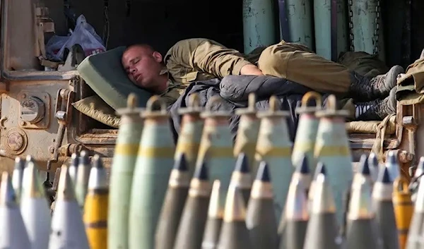 An Israeli soldier sleeps on a truck behind mobile artillery unit shells near the Israel-Gaza border in 2014. (AP photo)