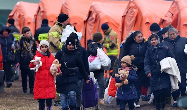 People walk past tents on their way to board a train after crossing the border from Ukraine to Poland, following the Russian invasion of Ukraine, at the border checkpoint in Medyka, Poland, March 9, 2022 (Reuters).