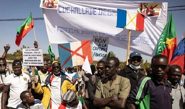 Demonstrators hold placards during a protest to to demand the departure of France's military forces, in Ouagadougou, on January 20, 2023 (AFP)