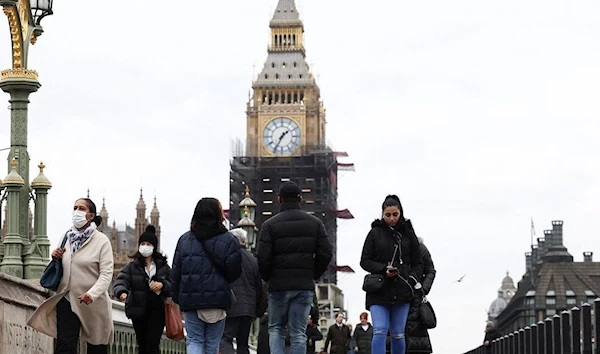 People wearing protective face masks walk over Westminster Bridge in front of the Elizabeth Tower, more commonly known as Big Ben, in London, Britain, December 15, 2021. (REUTERS)