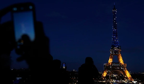 People photograph Paris' Eiffel Tower as it is lit with Ukraine's colors on February 25, 2022 (AP).