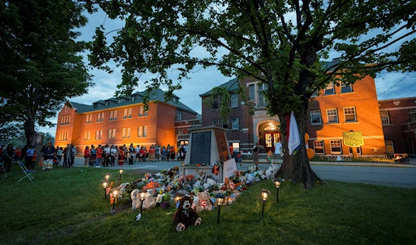 People gather to listen to drummers and singers at a memorial in front of the former Kamloops Indian Residential School.