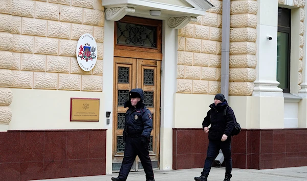 A Russian police officer and a man walk at the Latvian Embassy's building in Moscow, Russia, Tuesday, Jan. 24, 2023 (AP Photo/Alexander Zemlianichenko)